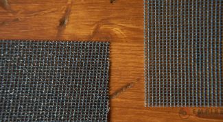 Two mesh abrasive sanding sheets with holes throughout for dust collection lay on a wooden table. Mesh abrasive sanding sheets are best used for tasks where dust extraction is a priority