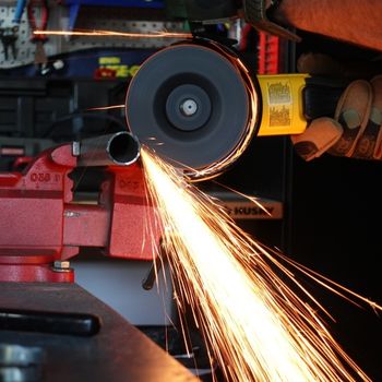 Angle grinder cutting metal pipe with cutoff disc