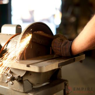 Bench grinder in action with sparks, highlighting Empire Abrasives 8" sanding discs for shaping and smoothing metal surfaces