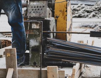 Industrial hydraulic rebar cutting machine in use at a construction site.