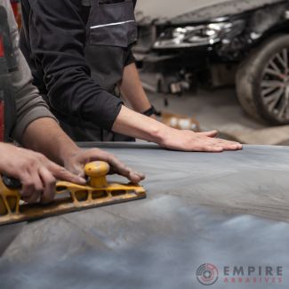 Professional using longboard sander on car body for thorough surface preparation before painting