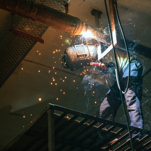Welder performing a weld overhead on a pipe