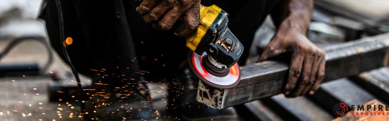Worker skillfully using a handheld angle grinder on metal, with sparks flying, showcasing the tool's heavy-duty grinding capabilities