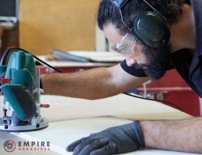 Woodworker wearing protective goggles and using a power sander